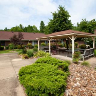 A charming garden area featuring a gazebo, surrounded by lush greenery and a pathway.