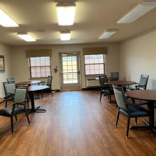 A spacious and well-lit room featuring tables and chairs, ideal for gatherings or activities.