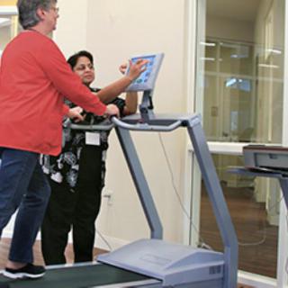 A person receives guidance while exercising on a treadmill.