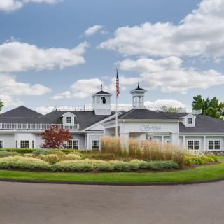 A well-landscaped building with a flagpole and a cloudy sky backdrop.