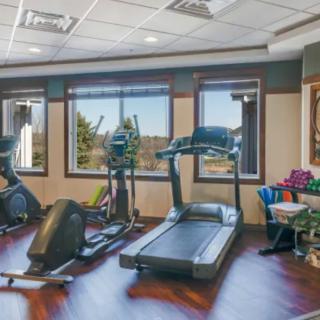 A well-lit gym with modern exercise equipment, including treadmills and an elliptical machine.