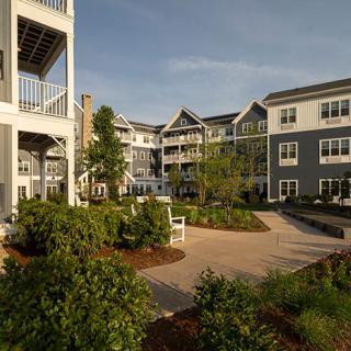 A modern apartment complex with well-maintained landscaping and outdoor seating.