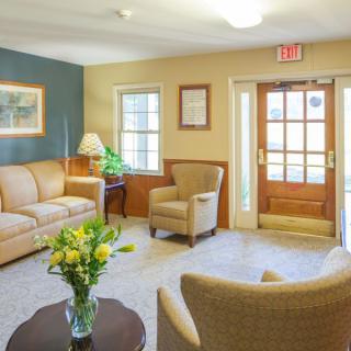 A cozy living room with comfortable seating, a wooden table with flowers, and natural lighting.