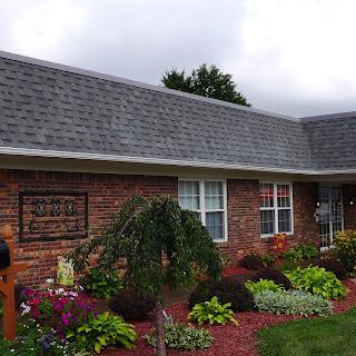 A picturesque brick building with vibrant landscaping under a cloudy sky.