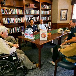 A group of people engaged in a meeting around a table in a library setting.