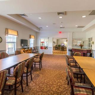 A spacious dining area with long tables, chairs, and large windows allowing natural light.