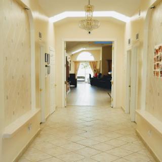 A well-lit hallway leading to a spacious area, with decorative walls and tiled flooring.