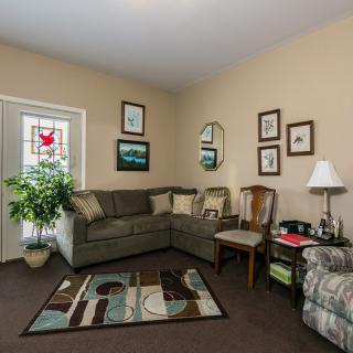 A cozy living room with a sectional sofa, armchair, and decorative elements including a rug, wall art, and a potted plant.