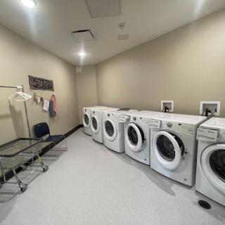 A spacious laundry room equipped with multiple washing machines and a drying rack.