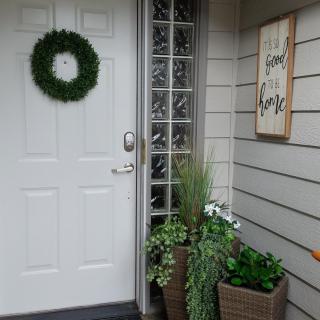A welcoming front porch with a wreath on the door and potted plants.