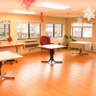 A spacious and well-lit indoor room featuring multiple tables and a cozy chair, decorated for a special occasion.