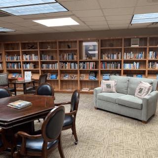 A cozy library space with bookshelves, a sofa, and seating area for reading.
