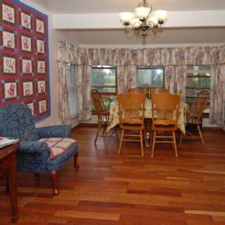 A cozy dining area featuring a wooden table surrounded by chairs and large windows with patterned curtains.