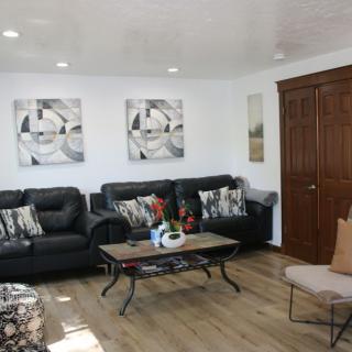 A modern living room with black sofas, a coffee table, and abstract artwork on the walls.
