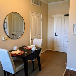 A cozy dining area with a small table set for two, featuring a round mirror on the wall.