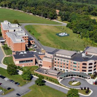 Aerial view of a large hospital complex surrounded by greenery and parking lots.