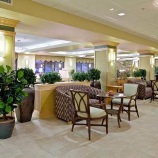 A spacious hotel lobby with comfortable seating and lush plants.