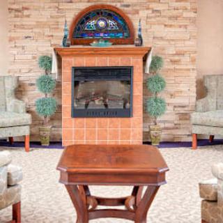 A cozy living room setup with a central fireplace, surrounded by elegant chairs and a wooden table.