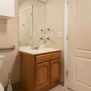 A small bathroom with a wooden vanity, mirror, and closed door.