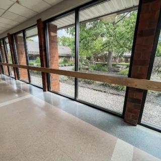 A spacious corridor with large windows offering a view of the greenery outside.