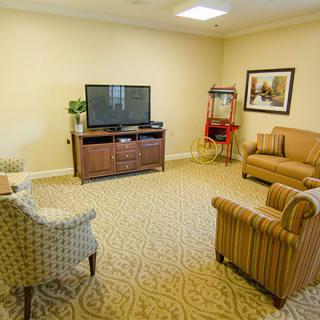 A cozy living room with a TV, sofas, chairs, and a popcorn machine.