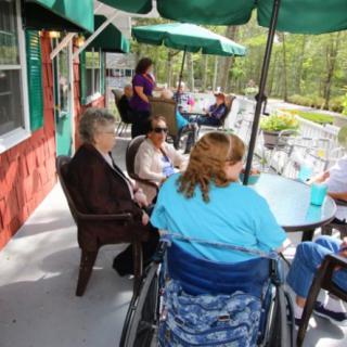 A group of people socializing on an outdoor patio with umbrellas.
