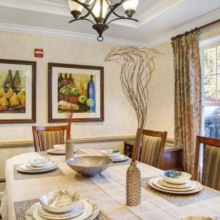 A beautifully decorated dining room featuring a set table with elegant dishware, framed artwork on the walls, and a stylish chandelier overhead.