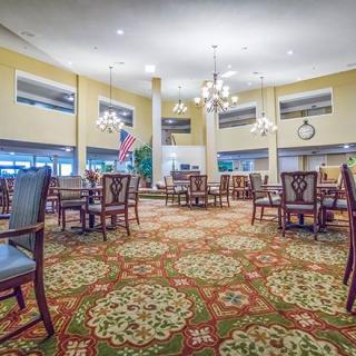 Spacious and elegantly decorated lobby area with multiple tables, chairs, and chandeliers.