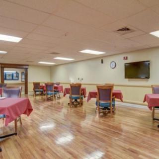An empty dining room with neatly arranged tables and chairs on a hardwood floor.