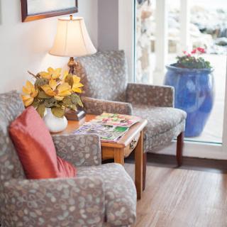A cozy corner of a living room featuring comfortable chairs, a lamp, and decorative elements.