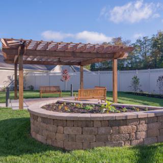 A serene garden space featuring a wooden pergola, well-maintained flowerbeds, and inviting seating areas.
