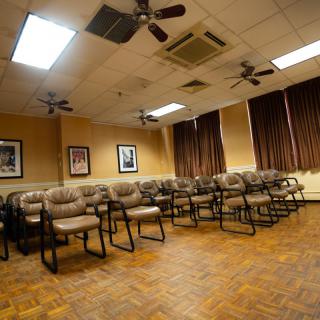 An empty conference room with rows of chairs and ceiling fans.