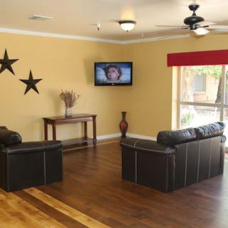 A cozy living room with a sofa set, TV mounted on the wall, and decorative elements such as wall stars and a vase.