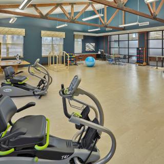 A spacious gym featuring various exercise equipment and a bright, open design.