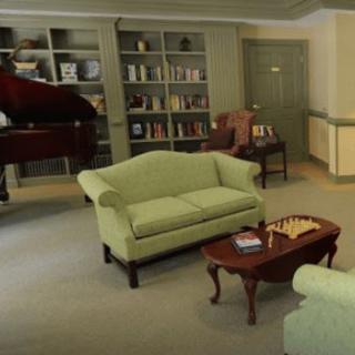 A cozy living room featuring a bookshelf, piano, and seating area with a chessboard on the coffee table.