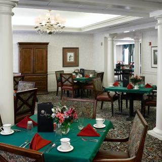 A neatly arranged dining room with tables set for a meal, featuring a chandelier and elegant decor.