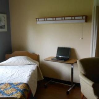 A minimalist hospital room with a bed, chair, and a small desk.