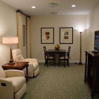 A cozy living room with comfortable seating, artwork on the wall, and warm lighting.