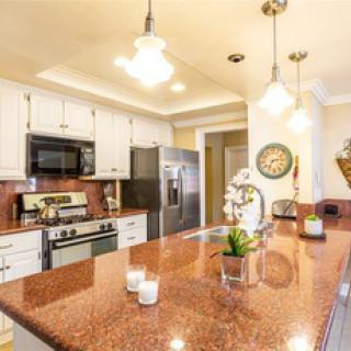 A modern kitchen with white cabinets, stainless steel appliances, and a large granite countertop.
