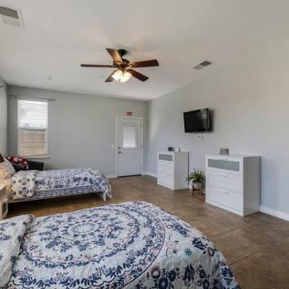 A spacious bedroom with two beds, a ceiling fan, and a mounted TV.