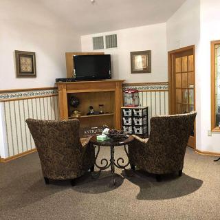 Cozy sitting area with two chairs facing a TV in a warmly decorated living room.