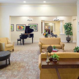 A cozy living room with a sofa, armchairs, and a grand piano.