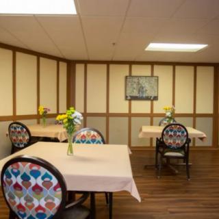 A cozy dining area with decorated chairs and tables adorned with flowers.