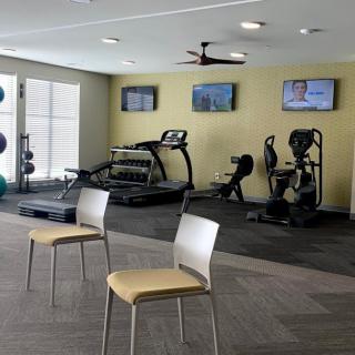 A modern gym with treadmills, stationary bikes, and multiple televisions.