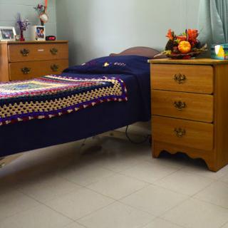 A cozy bedroom featuring a single bed with a colorful blanket and a wooden nightstand adorned with decorative items.