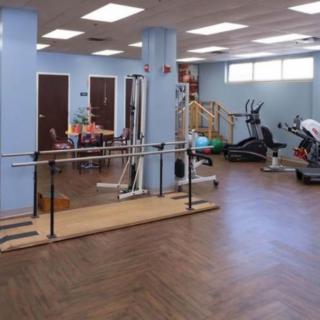 A physical therapy room with various exercise equipment and rehabilitation tools.