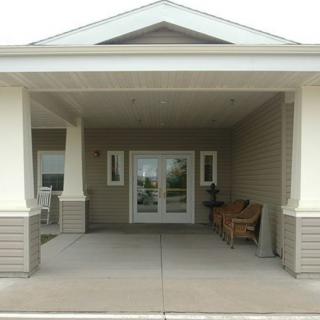A covered entrance to a building with a porch and double doors.