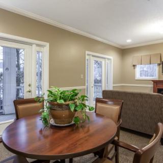 A cozy living room area with a wooden table, chairs, and a potted plant.