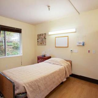 A minimalist hospital room with a single bed and a window providing natural light.