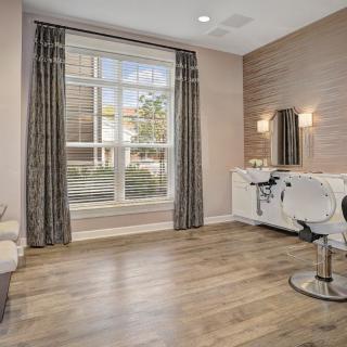 A modern salon interior with a large window, stylish chair, and mirror.